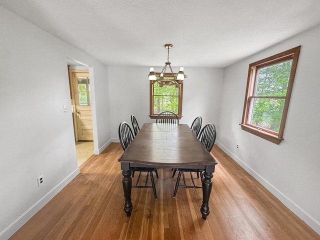 dining area with baseboards, light wood-style floors, and a chandelier