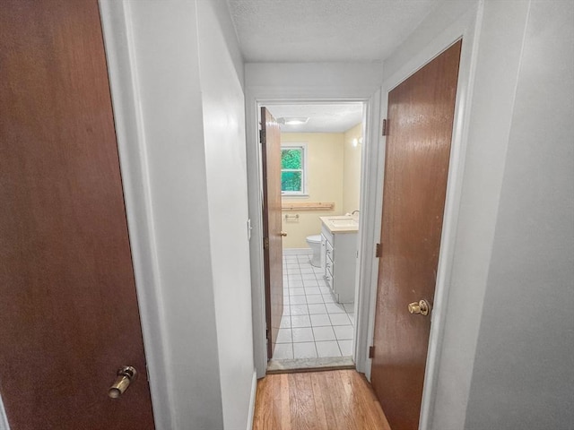 corridor featuring a sink and light wood finished floors