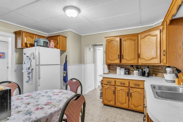 kitchen with decorative backsplash, wooden walls, sink, white refrigerator, and a paneled ceiling