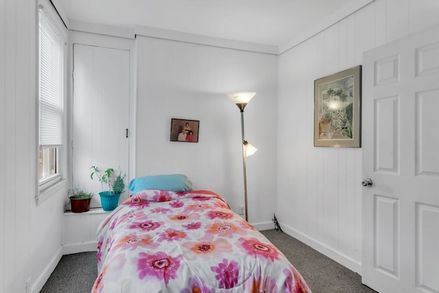 bedroom featuring wooden walls and dark colored carpet