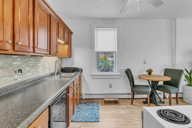 kitchen with decorative backsplash, light hardwood / wood-style flooring, sink, beverage cooler, and stainless steel range oven