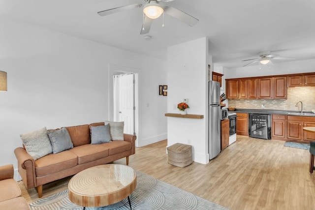 living room with sink, light wood-type flooring, and ceiling fan