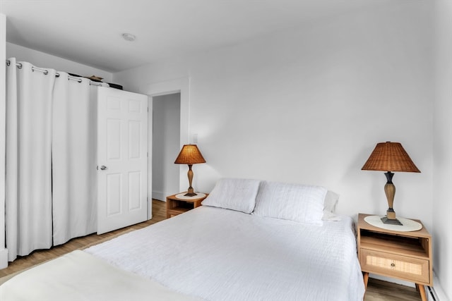 bedroom featuring a baseboard heating unit and hardwood / wood-style flooring