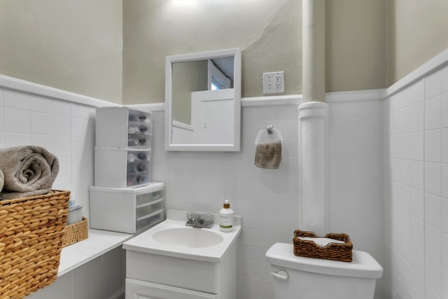 bathroom featuring vanity, toilet, and tile walls