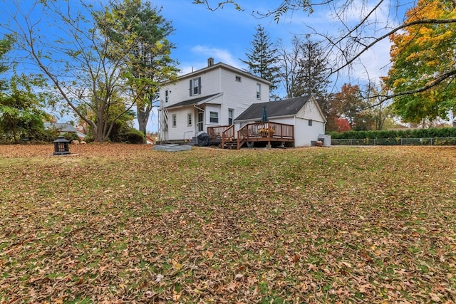 rear view of property with a wooden deck and a lawn