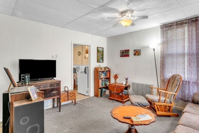 carpeted living room featuring radiator, ceiling fan, and washing machine and dryer