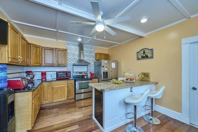 kitchen with tasteful backsplash, wall chimney exhaust hood, a peninsula, appliances with stainless steel finishes, and dark wood-style floors