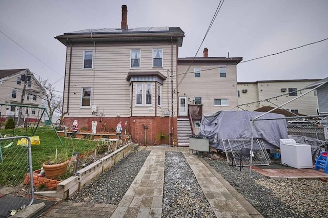 back of property with a chimney and fence