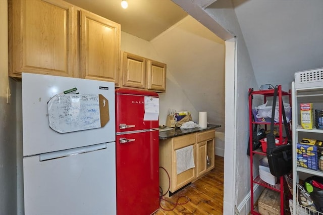 kitchen with refrigerator, vaulted ceiling, dark countertops, wood finished floors, and freestanding refrigerator