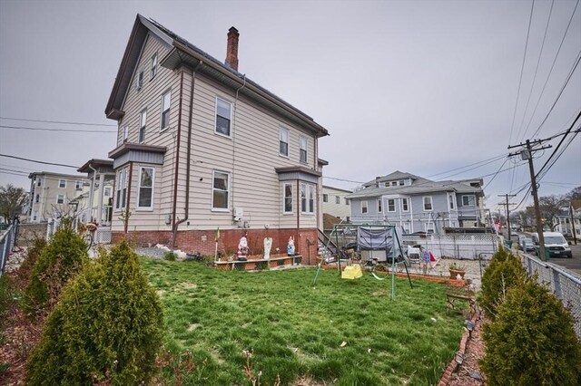 rear view of house featuring a lawn and fence
