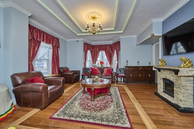 living room featuring a wealth of natural light, wood finished floors, an inviting chandelier, and a raised ceiling