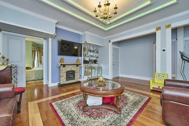 living room featuring a fireplace, wood finished floors, baseboards, and an inviting chandelier