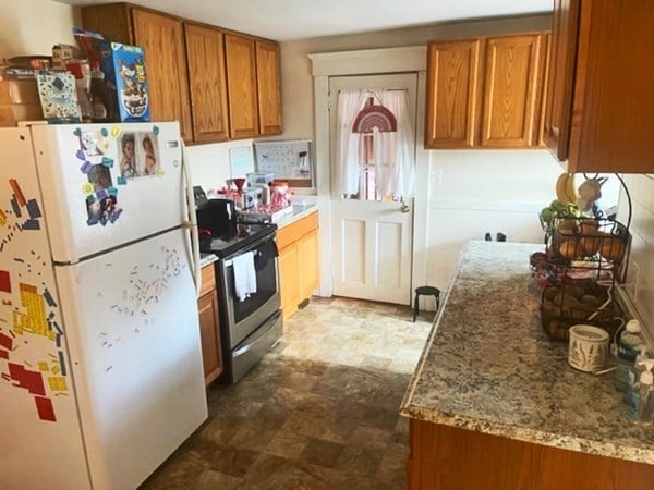 kitchen featuring tile floors, stainless steel range with electric cooktop, white fridge, and light stone counters