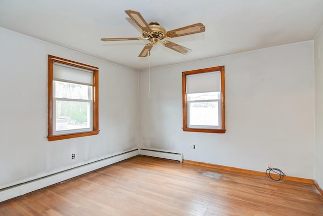 spare room featuring light wood-type flooring, a baseboard radiator, a wealth of natural light, and ceiling fan