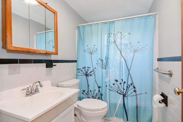 bathroom featuring walk in shower, vanity, toilet, and tile walls