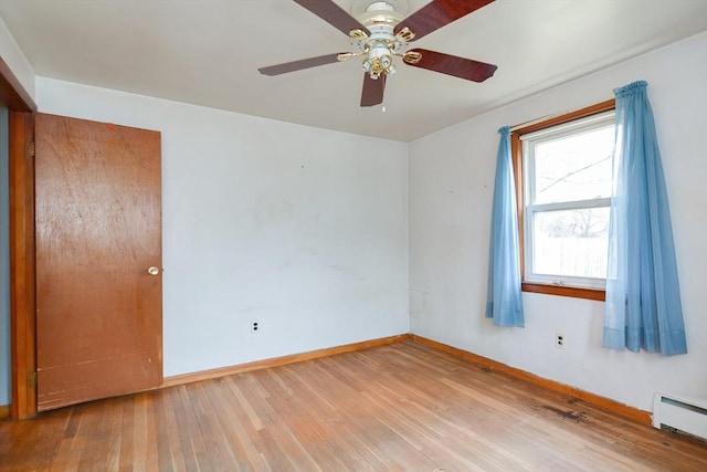 empty room featuring hardwood / wood-style floors, ceiling fan, and a baseboard heating unit