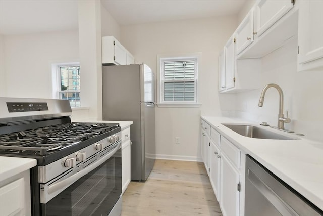 kitchen featuring light wood-style flooring, a sink, stainless steel appliances, light countertops, and white cabinetry