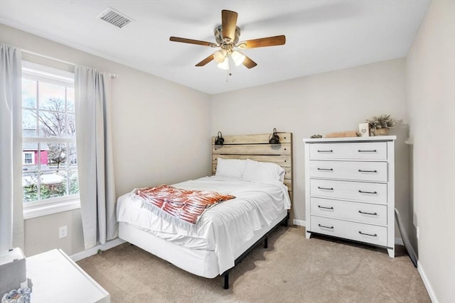 bedroom featuring ceiling fan, light carpet, and multiple windows