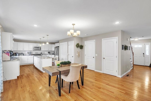 dining space featuring light hardwood / wood-style flooring and a chandelier