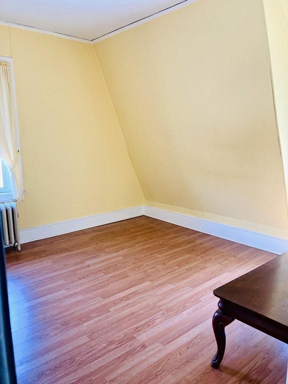 1123 S Broadway, East Providence, RI 02914 - spare room featuring radiator heating unit, wood finished floors, baseboards, and ornamental molding