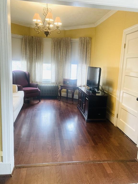 1123 S Broadway, East Providence, RI 02914 - living area featuring a chandelier, dark wood-style floors, ornamental molding, and radiator heating unit