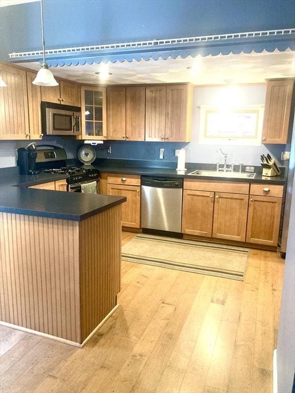 1123 S Broadway, East Providence, RI 02914 - kitchen with stainless steel appliances, dark countertops, a sink, and light wood-type flooring