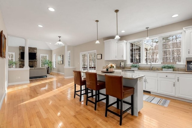 kitchen with a kitchen bar, a sink, white cabinetry, and light wood-style floors