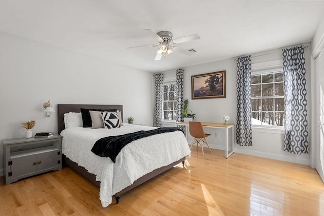 bedroom featuring light wood-style floors, visible vents, baseboards, and ceiling fan