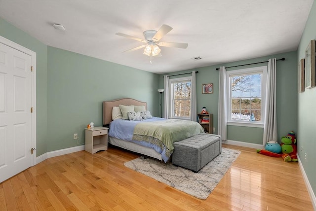 bedroom with light wood finished floors, baseboards, visible vents, and ceiling fan