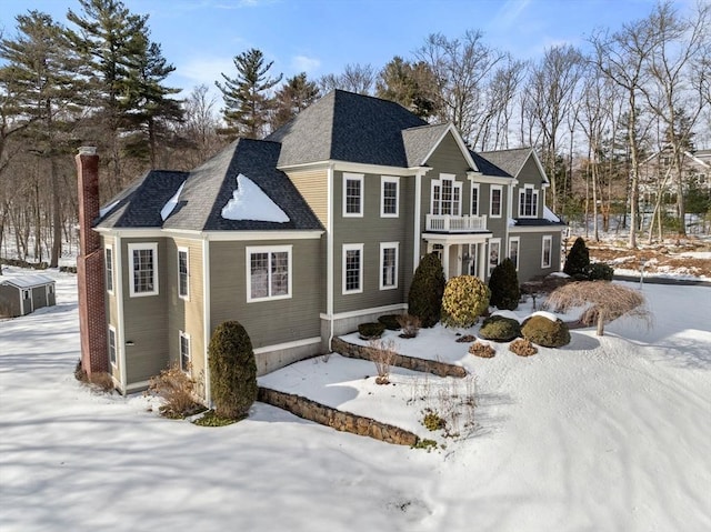 view of front of home featuring a shingled roof, a chimney, and a balcony