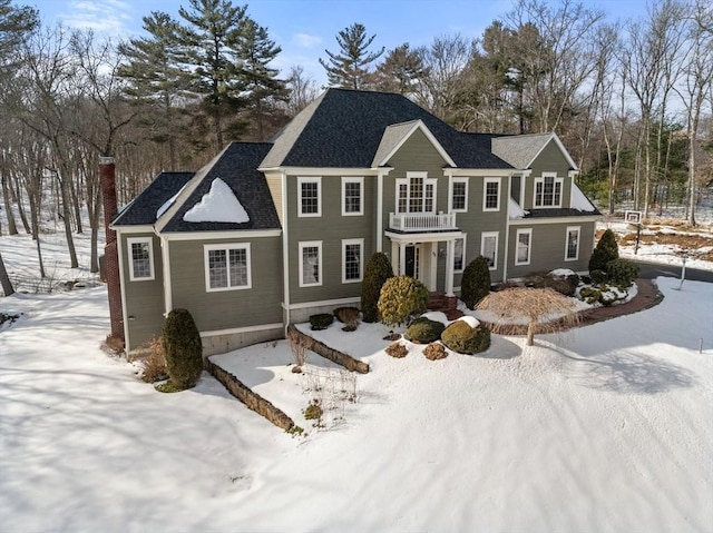 view of front of house with a balcony, driveway, and a chimney