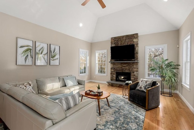 living room featuring vaulted ceiling, light wood finished floors, a fireplace, and a wealth of natural light