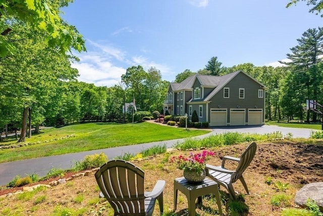 exterior space featuring an attached garage, aphalt driveway, and a yard