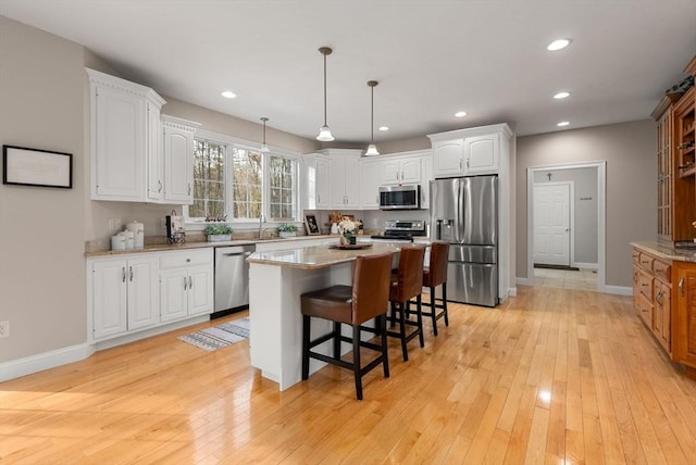 kitchen with light wood-type flooring, white cabinetry, stainless steel appliances, and a sink