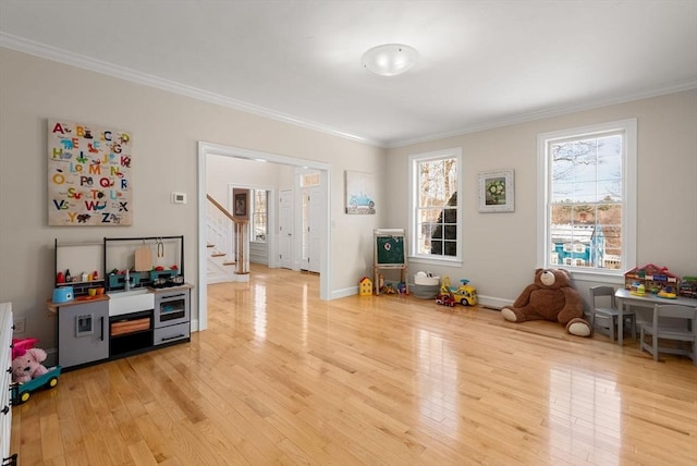 game room featuring ornamental molding, light wood-type flooring, and baseboards