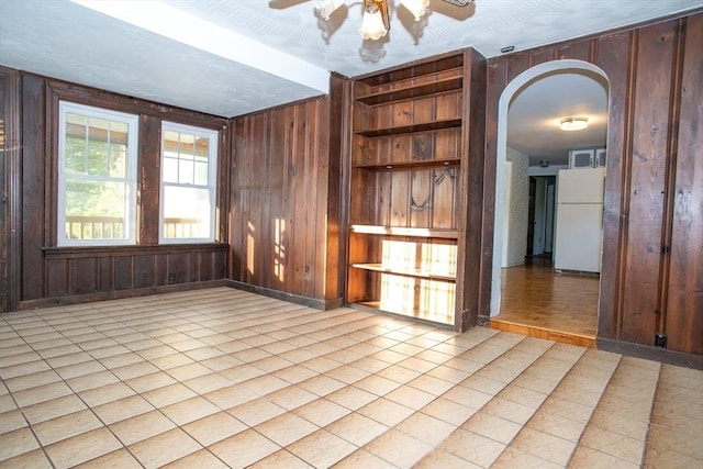 42 Giasson St, Hudson, MA 01749 - empty room featuring wood walls, arched walkways, ceiling fan, light tile patterned floors, and baseboards