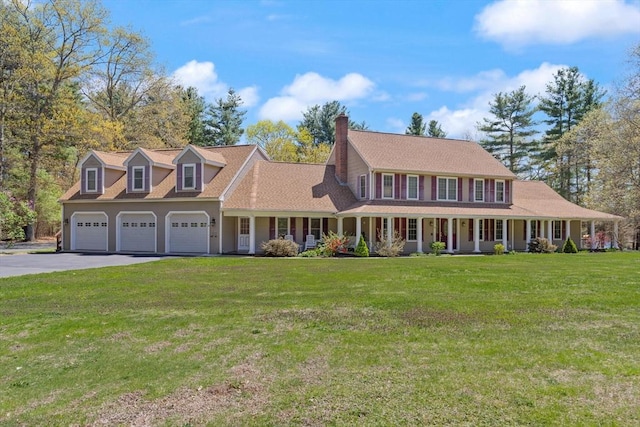 view of front of home with an attached garage, aphalt driveway, a front yard, a chimney, and a porch