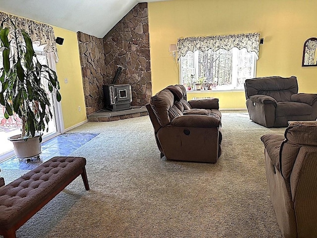 living area with carpet floors, a wood stove, lofted ceiling, and a healthy amount of sunlight