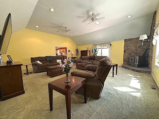 living area featuring ceiling fan, a wood stove, vaulted ceiling, carpet floors, and baseboards