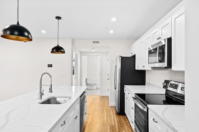 kitchen with a sink, visible vents, white cabinets, appliances with stainless steel finishes, and light wood-type flooring