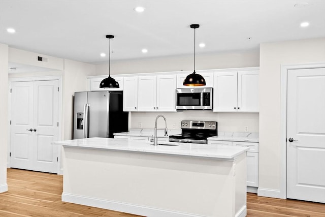 kitchen featuring light wood finished floors, stainless steel appliances, a kitchen island with sink, white cabinetry, and a sink