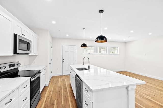 kitchen with a center island with sink, light wood-style flooring, stainless steel appliances, a sink, and recessed lighting