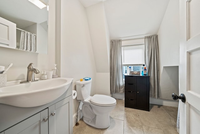 bathroom with tile patterned flooring, vanity, toilet, and vaulted ceiling