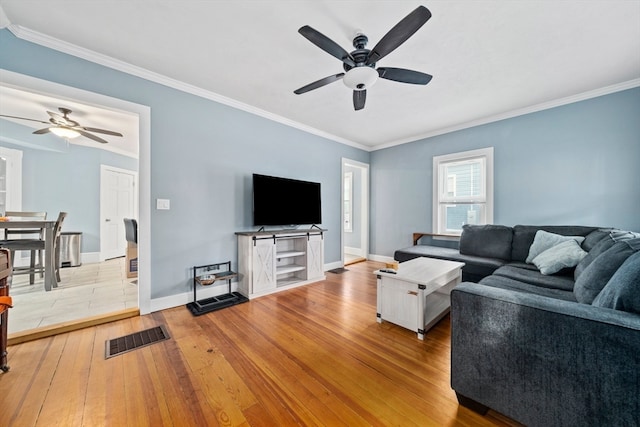 living room with ornamental molding, light wood-type flooring, and ceiling fan