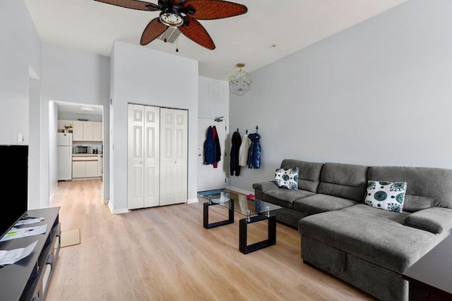 living area with baseboards, ceiling fan, and light wood-style floors
