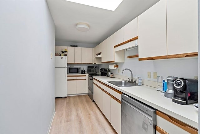 kitchen with light countertops, stainless steel appliances, under cabinet range hood, a sink, and white cabinets