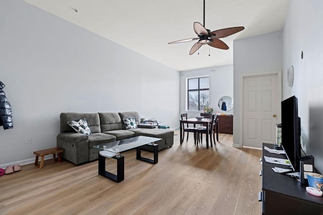 living area featuring baseboards, lofted ceiling, light wood-style flooring, and ceiling fan