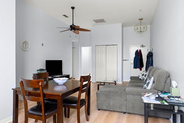dining space featuring light wood-style flooring, a towering ceiling, ceiling fan, and visible vents