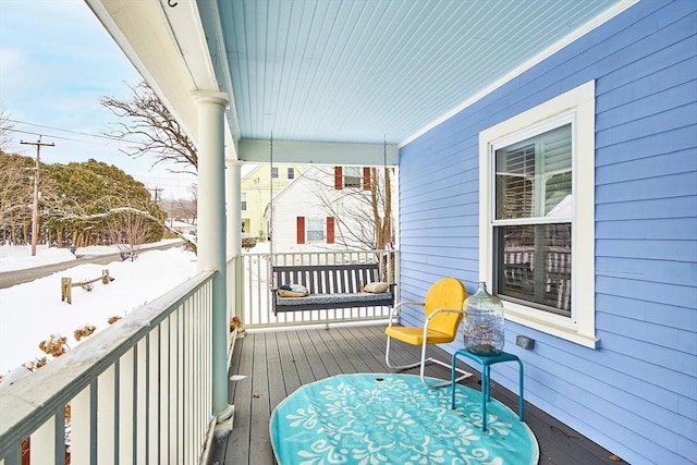 snow covered deck featuring a porch