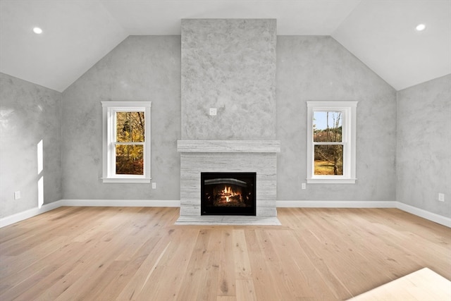 unfurnished living room featuring a fireplace, high vaulted ceiling, and light hardwood / wood-style flooring